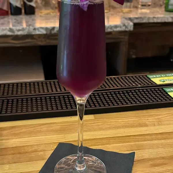 A purple-tinted Blue Lagoon cocktail in a stemmed glass on the Carib Soul BK bar