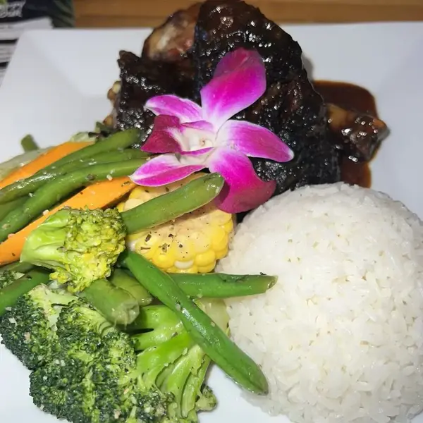 Jerk chicken plated with white rice, broccoli, green beans and corn at Carib Soul BK