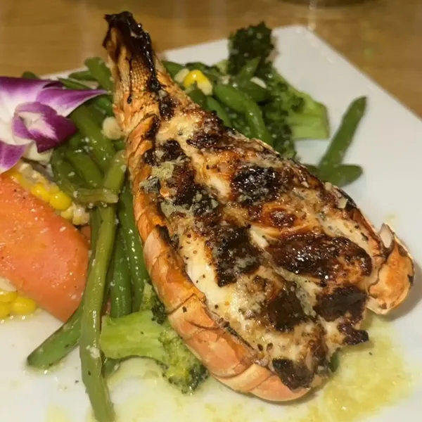 Grilled lobster tail with garlic butter, green beans, broccoli, carrots and corn at Carib Soul BK