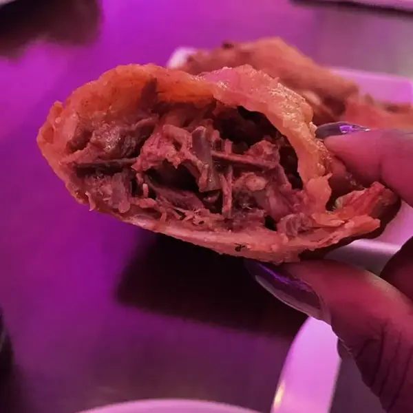 Close-up of an oxtail empanada cut open to show the shredded oxtail filling