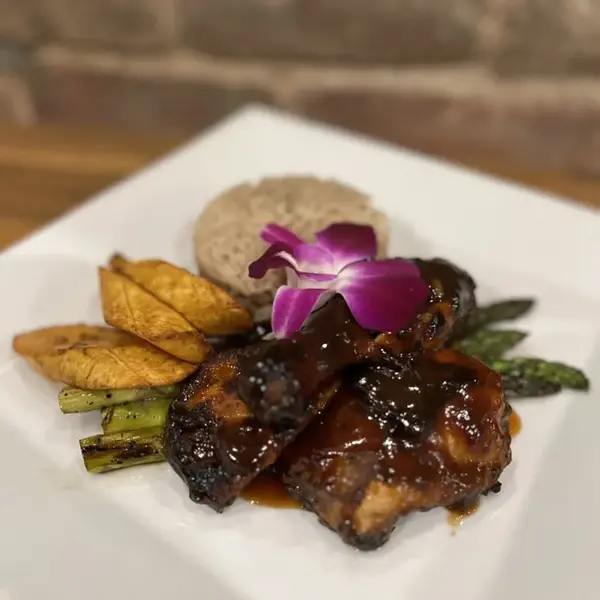 Red Stripe jerk chicken with rice and peas, sweet plantains and vegetables, garnished with an orchid, at Carib Soul BK